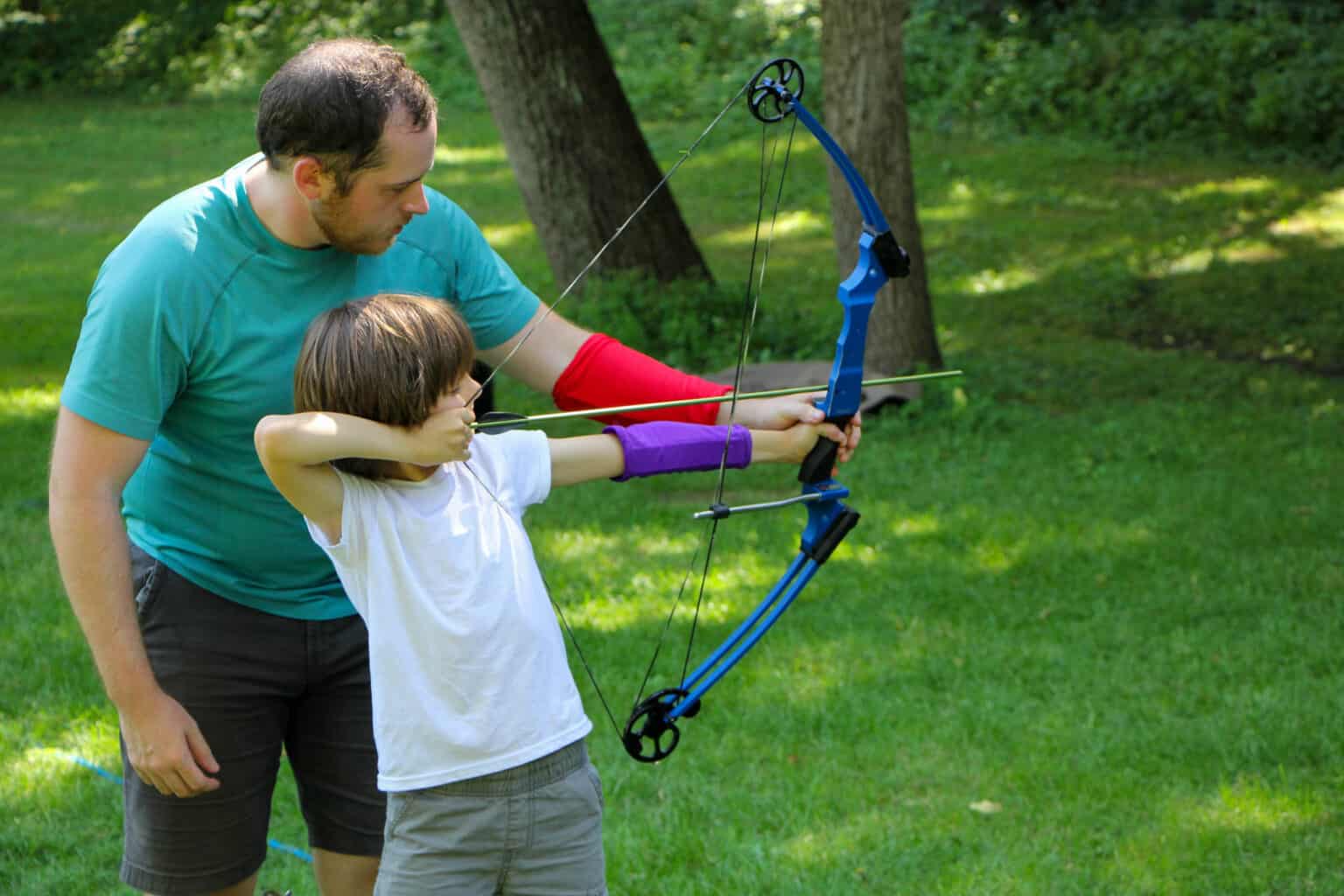 A man and a child enjoying archery at an Iowa summer camp.