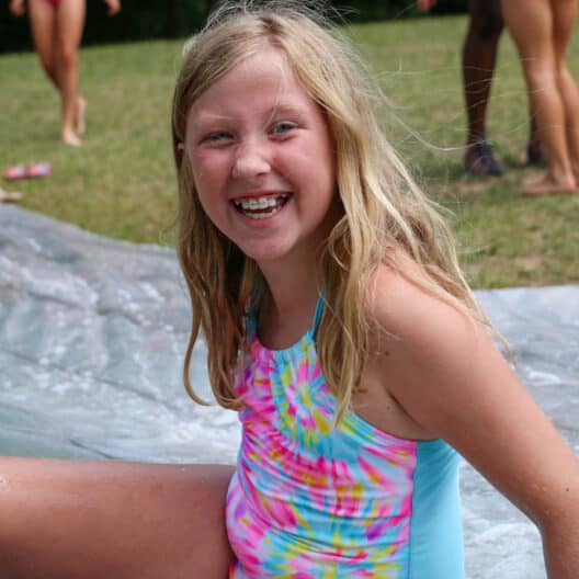 A girl at a summer camp in Iowa sliding down a water slide.