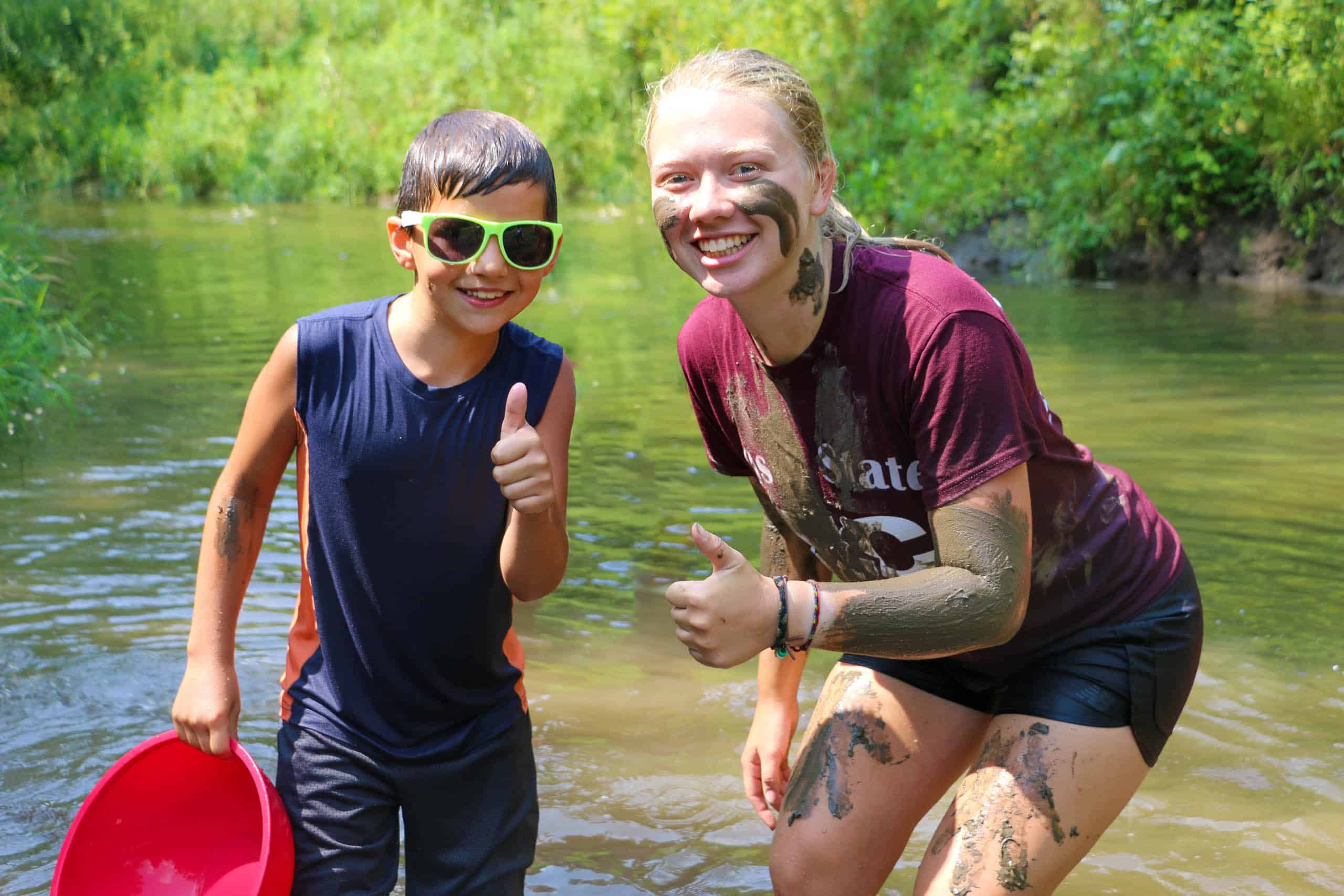 A woman and a boy participating in a summer camp activity in Iowa, with mud on their faces.