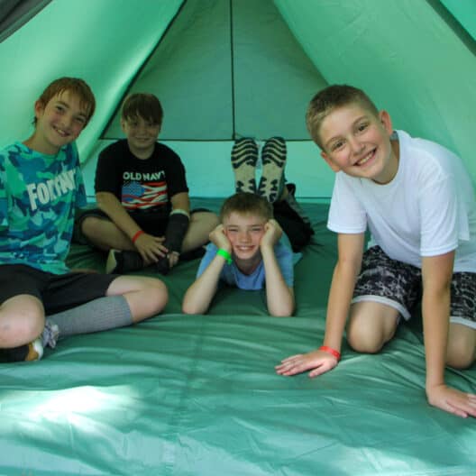 Four boys in a tent during summer camp in Iowa.