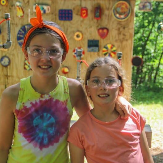Two girls in glasses posing for a picture at a summer camp in Iowa.