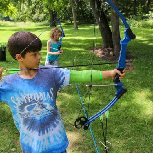 A young boy at a summer camp in Iowa practicing archery.