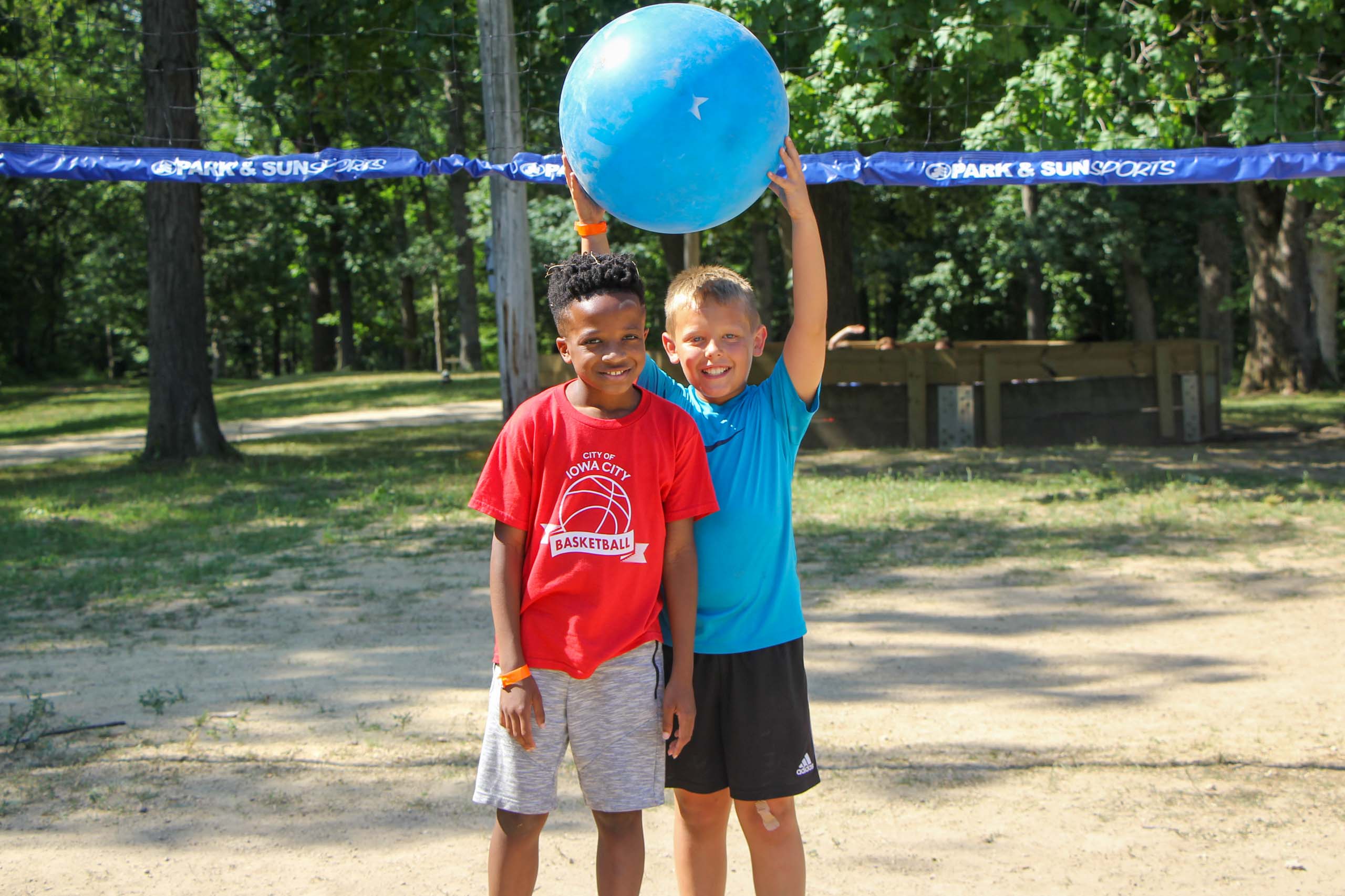 Two kids attending summer camp in Iowa playing with a blue ball.