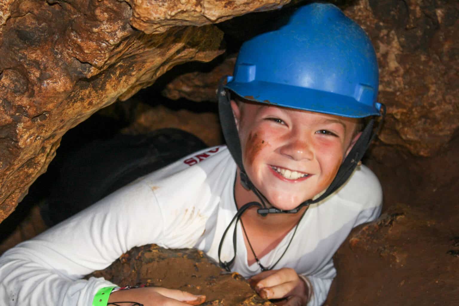 A boy wearing a helmet in a cave during summer camp in Iowa.