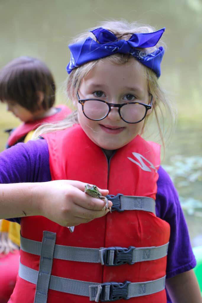 A girl at an Iowa summer camp holding a frog.