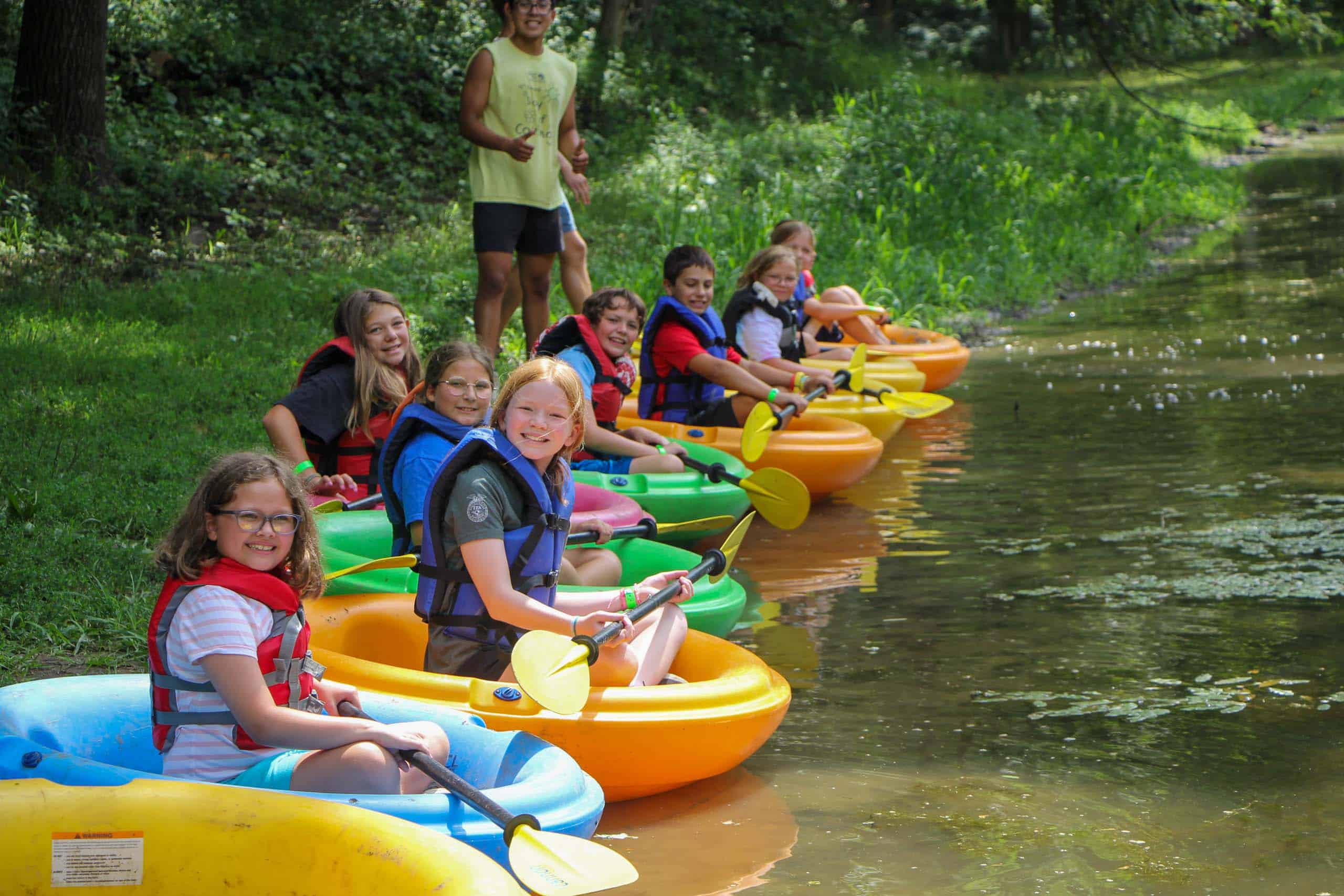 A group of kids at a summer camp in Iowa navigating rafts on a river.
