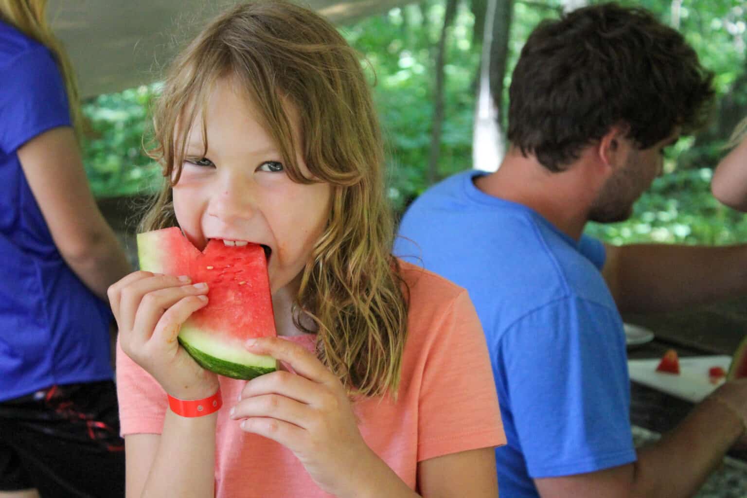 A young girl enjoying watermelon at a summer camp in Iowa.