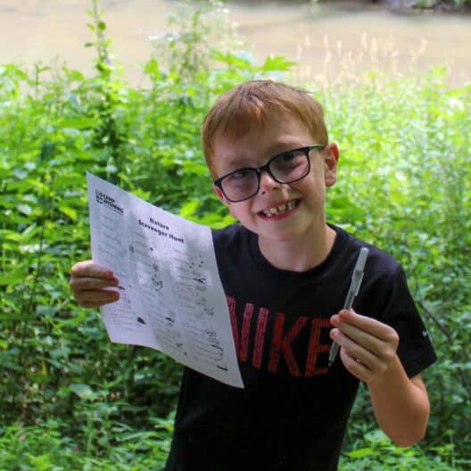 A boy participating in a scavenger hunt during summer camp in Iowa.
