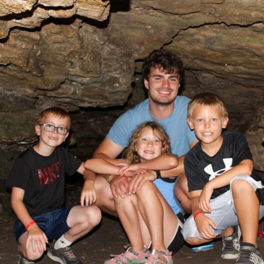A group of kids with their summer camp counselor posing for a picture in a cave in Iowa.