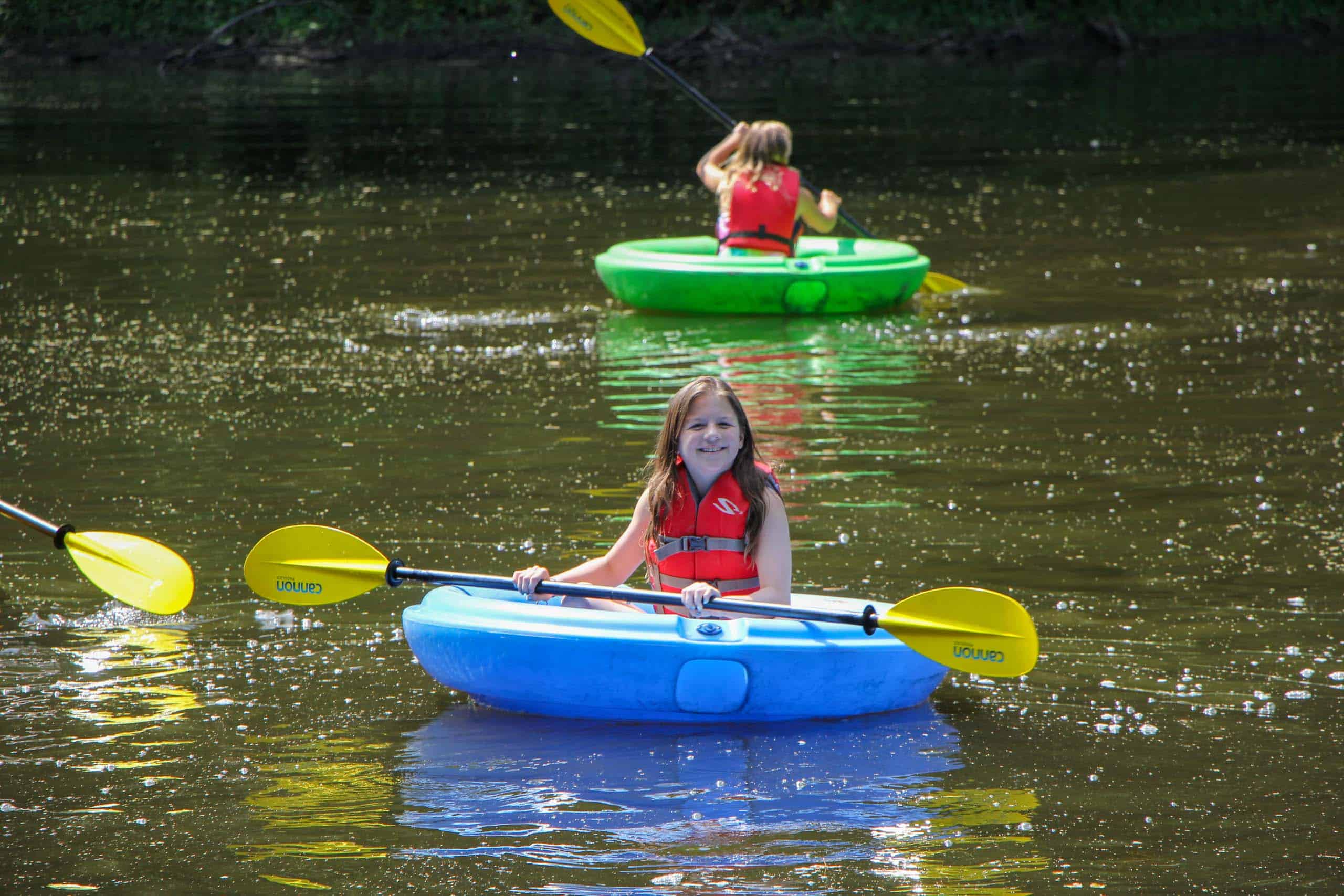 Kids at a summer camp in Iowa kayaking on a river.