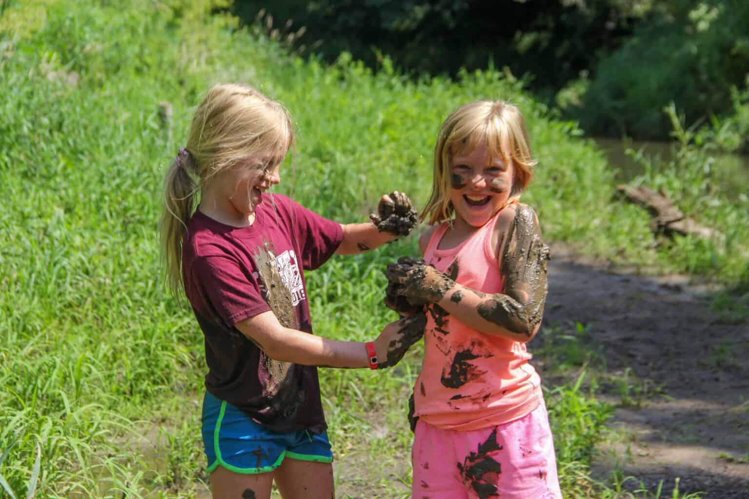 Two kids at a summer camp in Iowa playing in the mud.