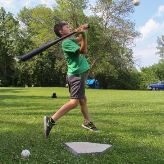 A boy swinging a baseball bat at summer camp in Iowa.