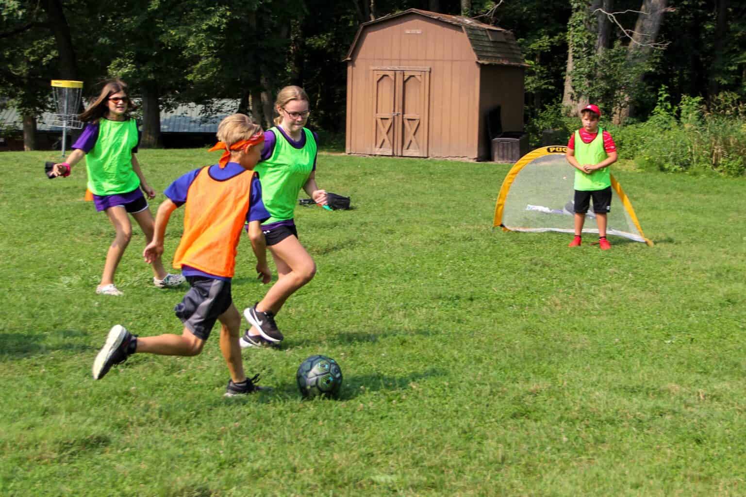 A group of kids at a summer camp in Iowa kicking a soccer ball.