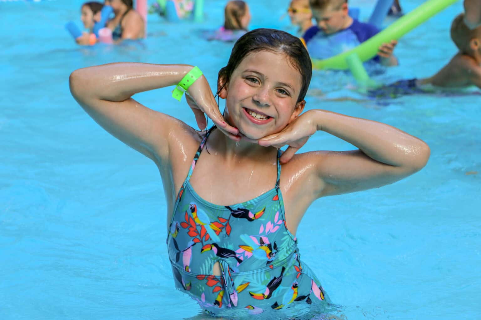 A young girl in a swimsuit at an Iowa summer camp swimming pool.
