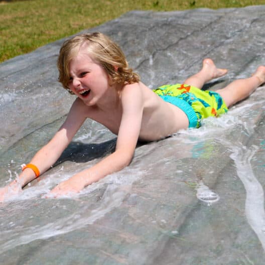 A young boy enjoying a water slide at summer camp in Iowa.