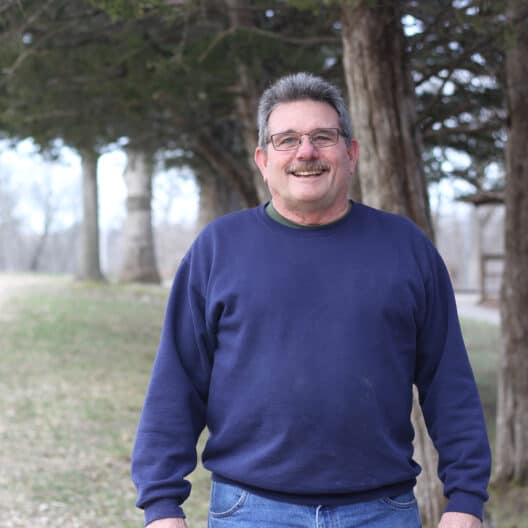 Pat Hanrahan in front of the Cedar Trees at Deer Center