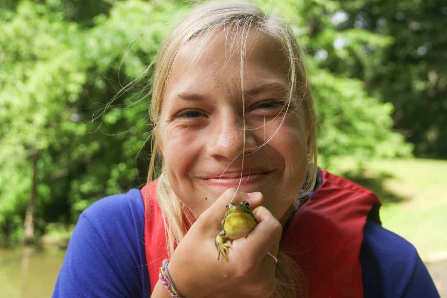 A girl holding a frog at a summer camp in Iowa.