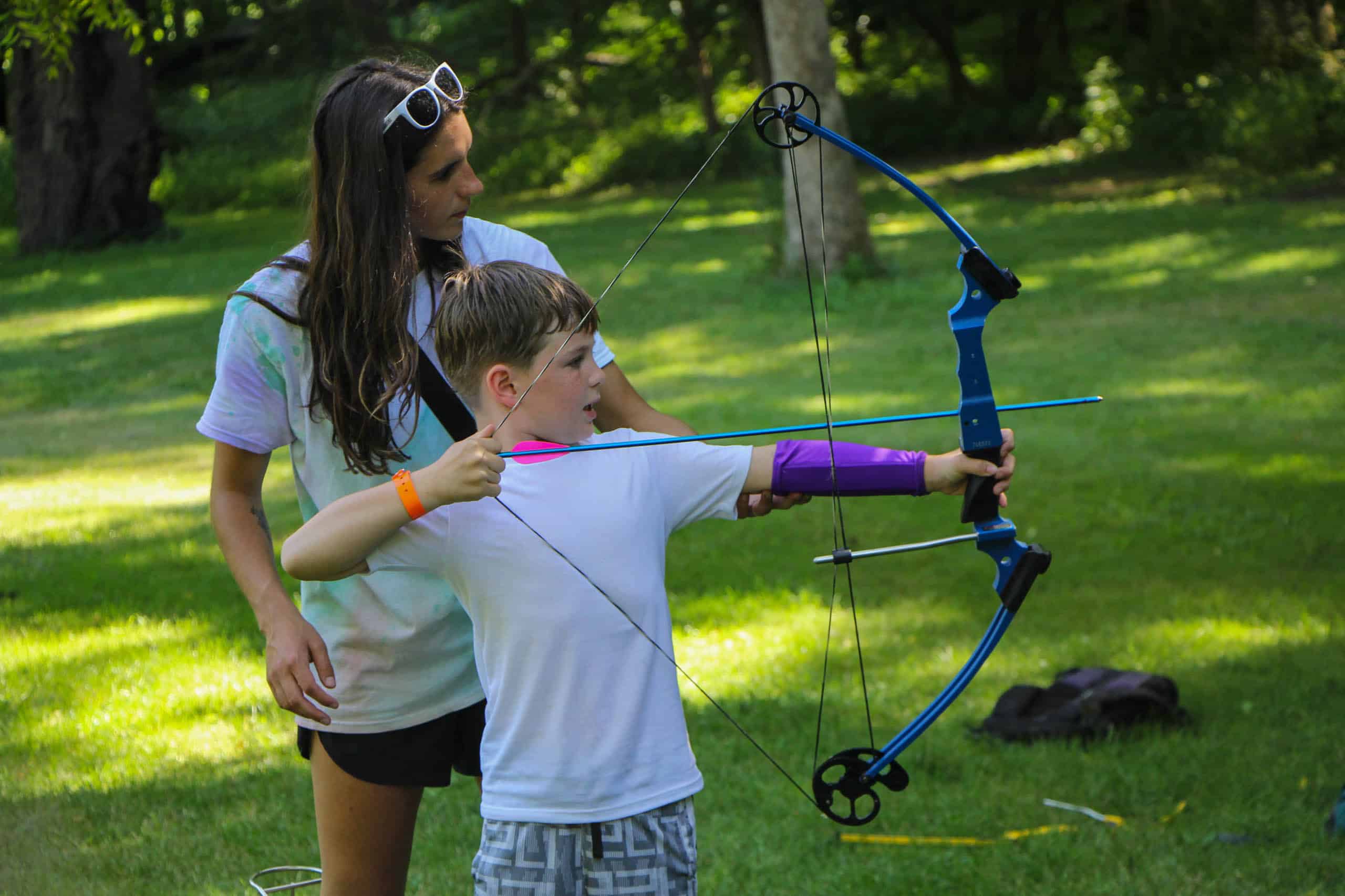 A young boy at an Iowa summer camp learning to use a bow and arrow.