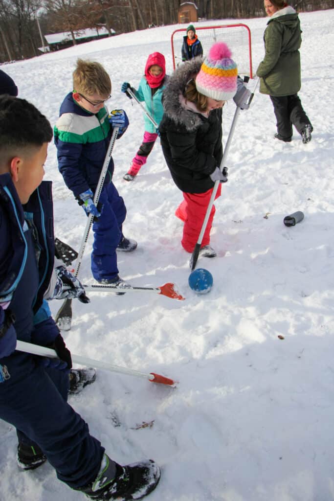 A group of Iowa kids playing Broomball in the snow at a campground.