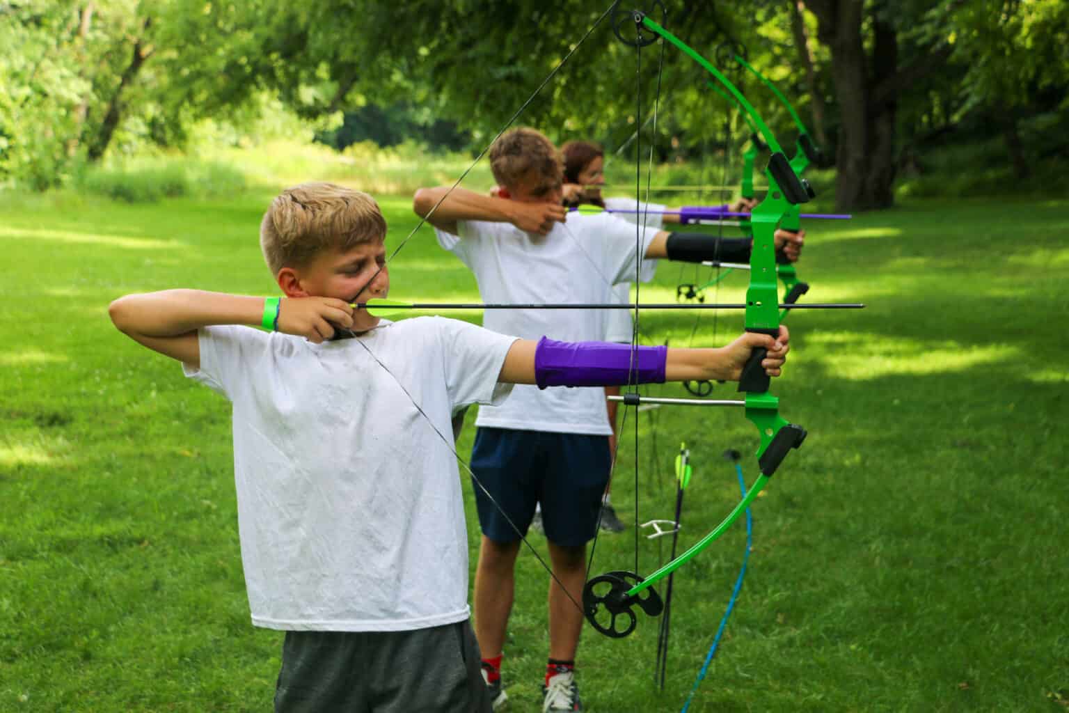 A group of kids practicing archery in a summer camp in Iowa.
