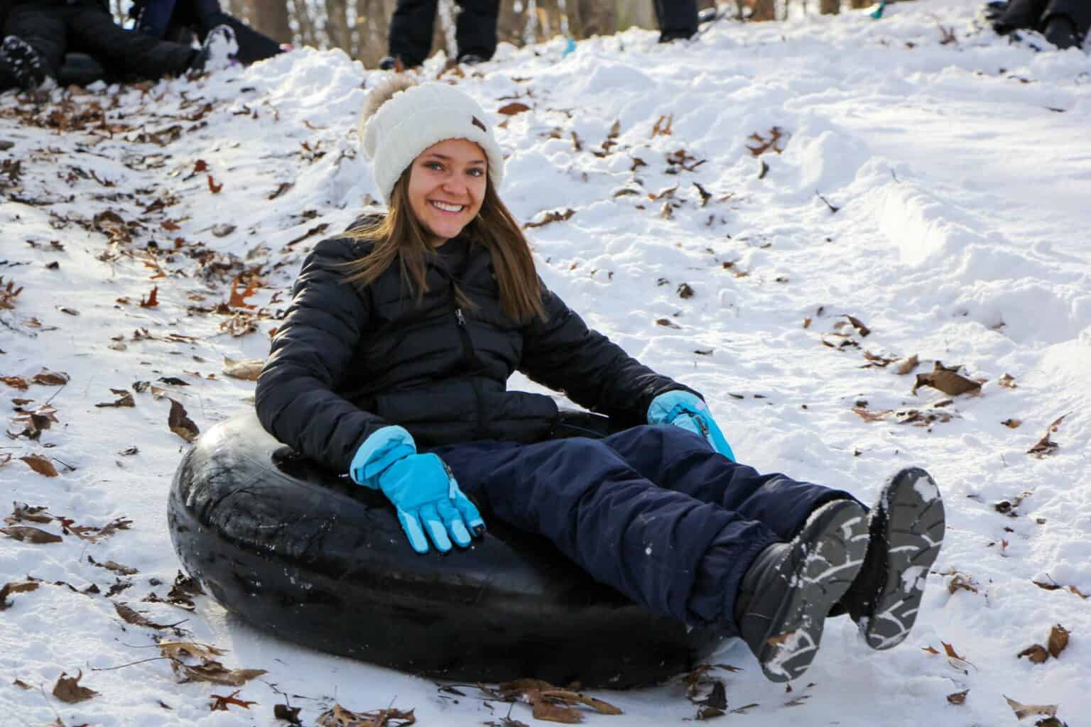 A woman sitting on a tube at an Iowa winter camp.