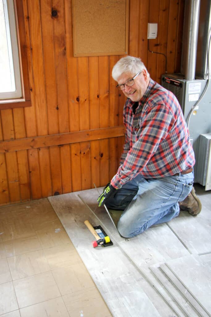 A man is laying tile in a room at an Iowa summer camp for kids.