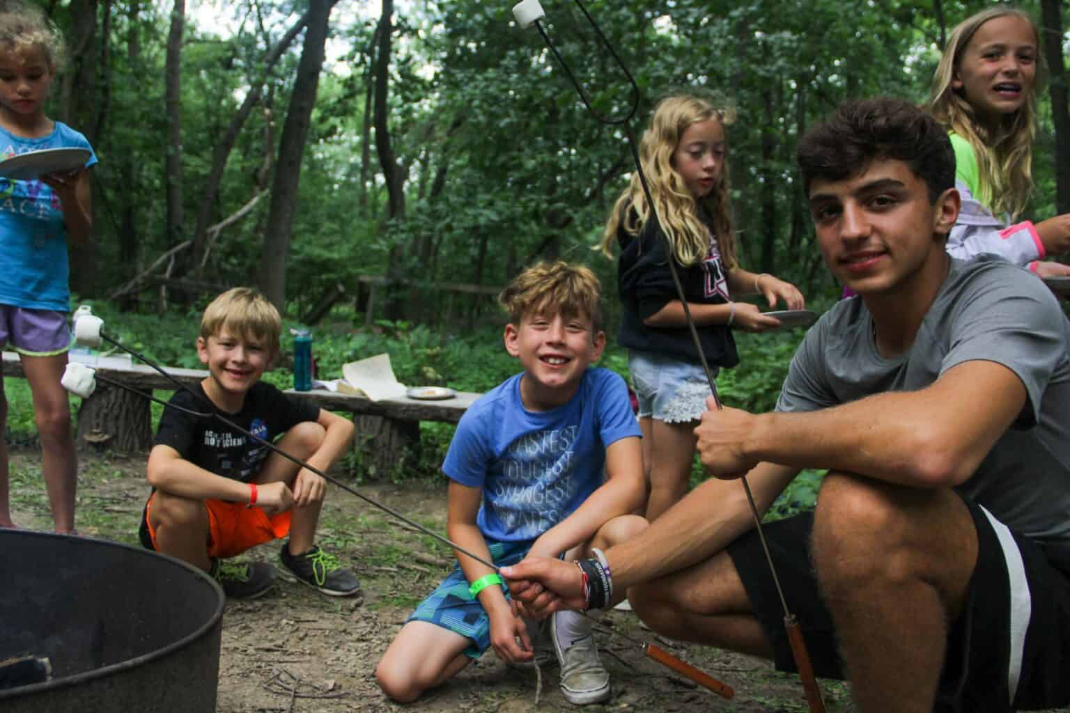 A group of kids at an Iowa summer camp gathered around a campfire.