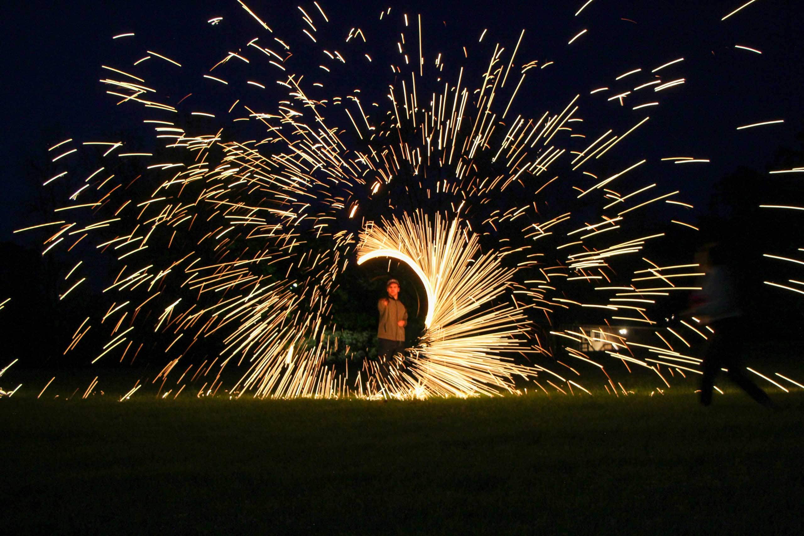 A person standing in a field with sparklers during summer camp in Iowa.