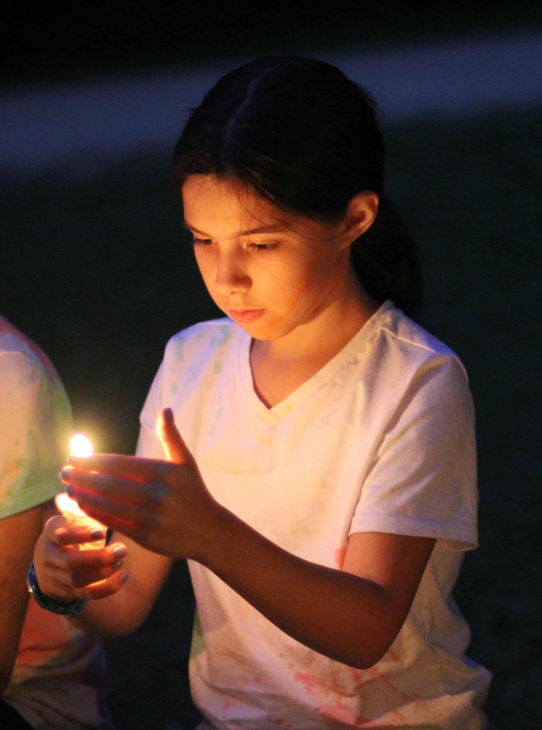 A kid at summer camp in Iowa holding a lit candle.