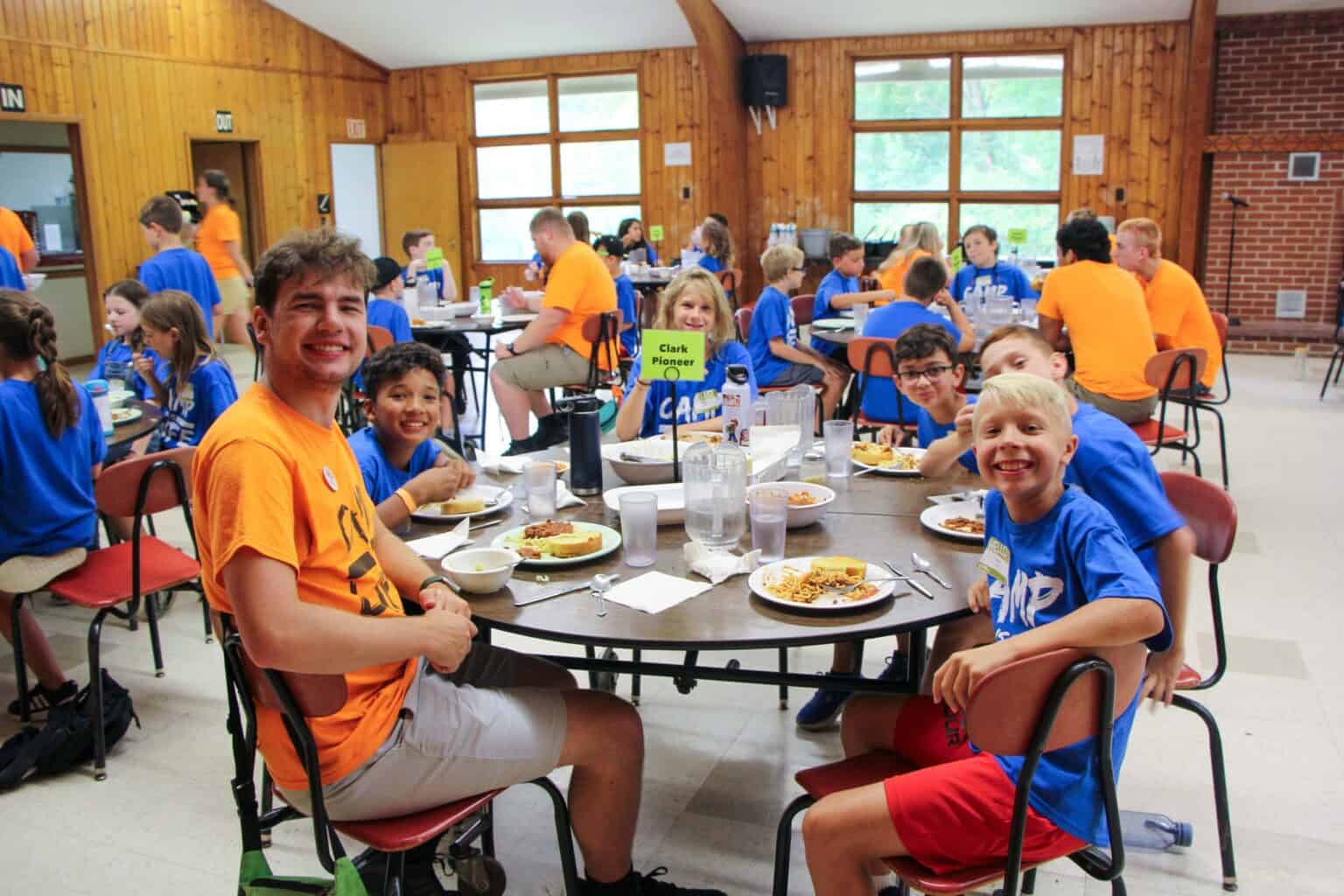 A group of kids eating at a table during summer camp in Iowa.