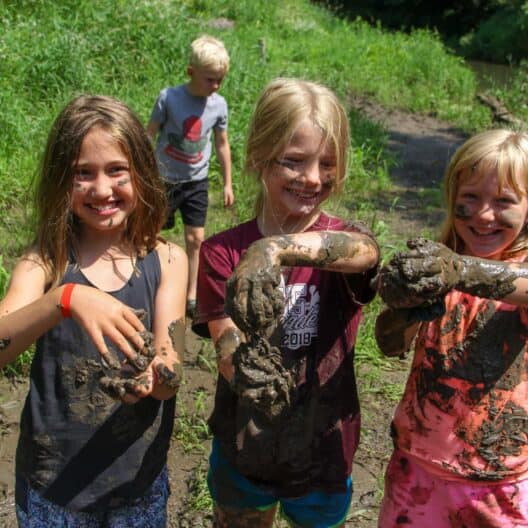 A group of kids at a summer camp in Iowa with mud on their hands.