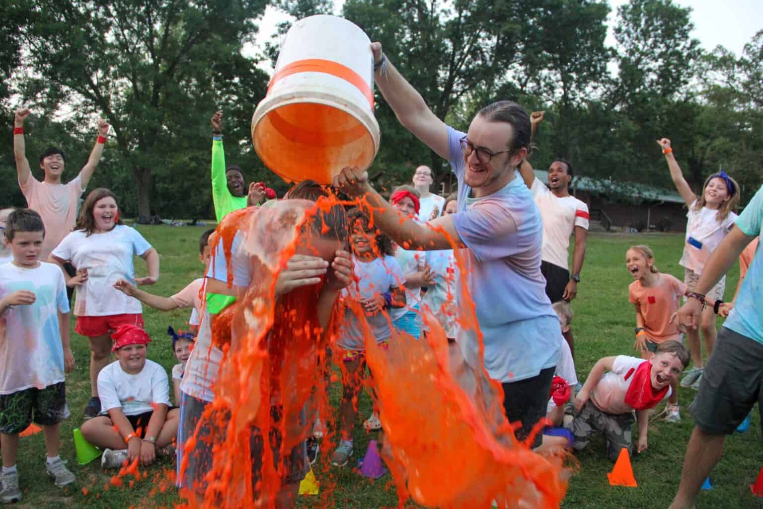 A group of kids at a summer camp in Iowa are throwing orange paint at each other.